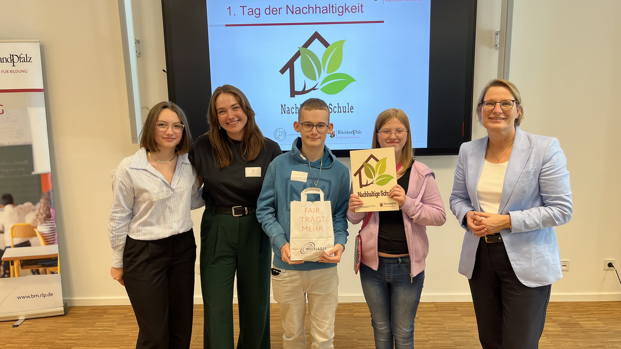 Auf dem Foto sehen Sie zwei Schülerinnen und Schüler der Förderschule gemeinsam mit Ministerin Hubig und zwei Vertreterinnen der LSV.