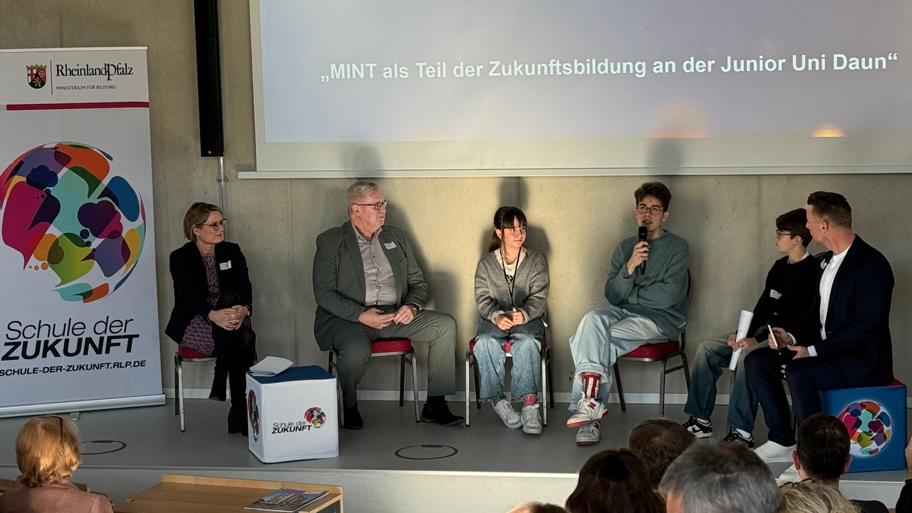 Bildungsministerin Hubig sowie Schülerinnen und SChüler und Vertreter der Junior Uni Daun auf dem Podium während einer Dikussion.